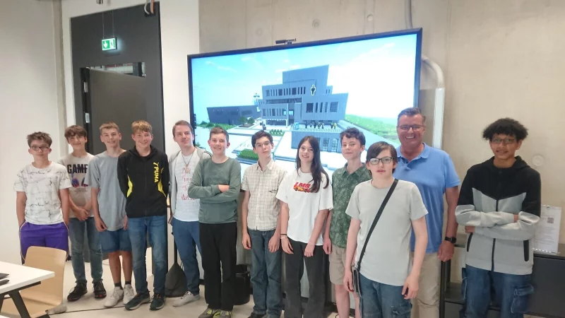 Der InnovationSPIN, gebaut in Minecraft, auf dem Bildschirm mit dem stolzen Team des Minecraft Bauprojekts, Thomas Mahlmann (zdi-Zentrum Lippe.MINT, Zweiter von rechts), Fabrice Magdanz (Kursleitung, F&uuml;nfter von links) und den Sch&uuml;lerinnen und Sch&uuml;lern. - &copy; Lippe Bildung