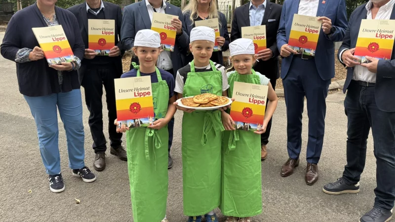 Dr. A. Heinrike Heil, Geschäftsführerin der Stiftung Standortsicherung Kreis Lippe (hintere Reihe von links), Dr. Albert Hüser, Vorsitzender des Lippischen Heimatbundes, Landrat Dr. Axel Lehmann, Iris Hansmann, Schulleiterin des Bildungshauses Weerth-Schule, Arnd Paas, Vorstandsvorsitzender der Sparkasse Paderborn-Detmold-Höxter, Klaus Drücker, Vorstandsvorsitzender der Sparkasse Lemgo, und Michael Gerd Schnittger, Fachstellenleiter des Lippischen Heimatbundes, stellen das Sachkundebuch "Unsere Heimat Lippe" vor. Louisa Drewel (vordere Reihe von links), Tim Diderich und Ionna Hollah präsentieren ihren lippischen Pickert, der frisch nach dem Rezept im neuen Buch gebacken wurde. - © Jan Schillmann
