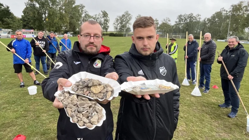 Timo Lenniger (links) und Erik Tappe zeigen einen Teil der Steine, Scherben, Plastik- und Metallst&uuml;cke, die Mitglieder des VfL Lieme bereits vom Sportplatz geklaubt haben. Am Dienstag wurde die Aktion abgebrochen, man kapituliere vor der unm&ouml;glichen Aufgabe, hei&szlig;t es von Seiten des Vereins. - &copy; Till Brand