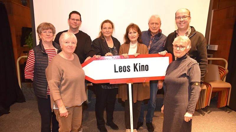 Ulrike Linsmeier, Margit Berghorn, Hendrik Glauer, Grita Behrens, Ponni L&uuml;king, Ingo Knabenreich, Ulrich Schumacher und Uli Aaltonen (von links) mit dem Schild, das auf das ehrenamtlich gef&uuml;hrte Kino hinweist. Foto: Karin Prignitz - &copy; Karin Prignitz