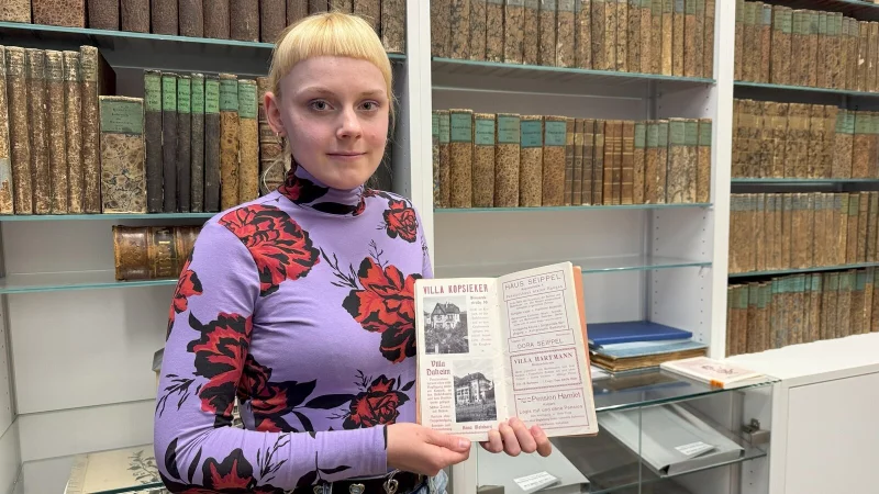 Pia Gillner hat das Schicksal der Familie Hamlet recherchiert, hier hält sie ein Pensionsregister aus der Nazi-Zeit in der Hand. Die jüdische Familie betrieb die Pension Hamlet in der Augustastraße 4. Die Familie wurde fast vollständig im Holocaust ermordet. - © Sven Kienscherf