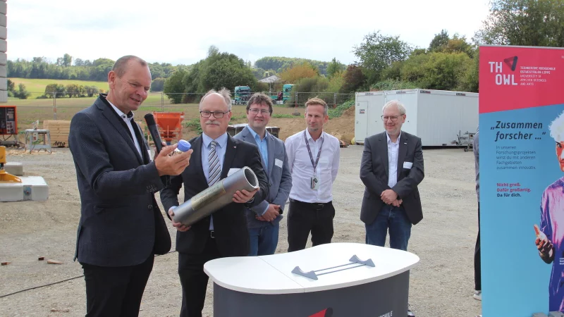 Hochschulpr&auml;sident Professor Dr. J&uuml;rgen Krahl (von links) best&uuml;ckt die Zeitkapsel mit einem Kraftstoff, der die Bezeichnung "RS 75" tr&auml;gt. Auch Projektleiter Professor Dr. Thomas Schulte, Martin Griese, Timo Broeker und Professor Dr. Holger Borcherding haben die Kapsel bei der Grundsteinlegung f&uuml;rs "Mobilit&auml;tszentrum UrbanLand" an der TH OWL in Lemgo bereits gef&uuml;llt. In dem Geb&auml;ude soll auch an E-Fuels geforscht werden. - &copy; Jens Rademacher