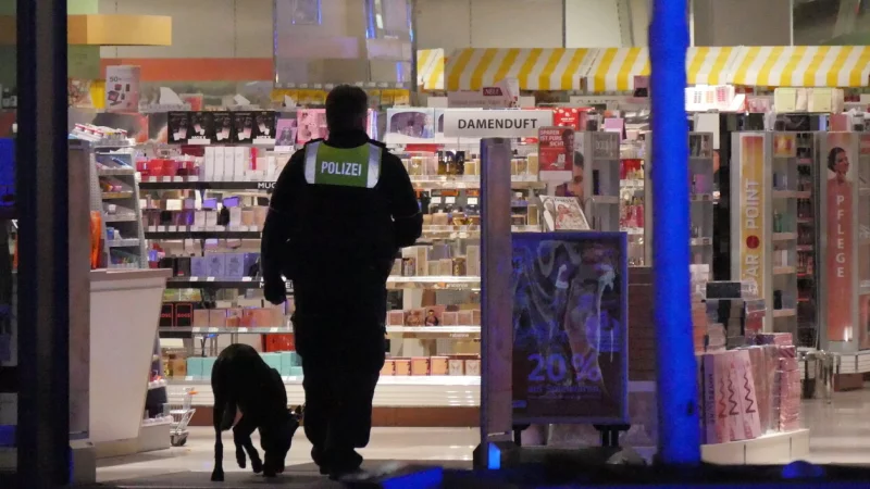 Mit einem Spürhund kontrolliert die Polizei nach Auslösung der Diebstahlwarnanlage im Müller, ob noch Personen im Geschäft sind. - © Jost Wolf