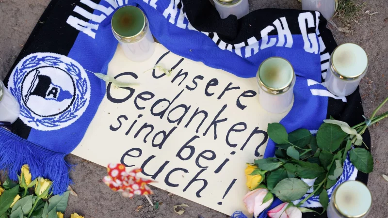 „Unsere Gedanken sind bei Euch!“, ist am Tatort in Messer-Anschlags in Bielefeld zu lesen. Fans haben Kerzen und Schal für die Opfer niedergelegt. - © Friso Gentsch/dpa