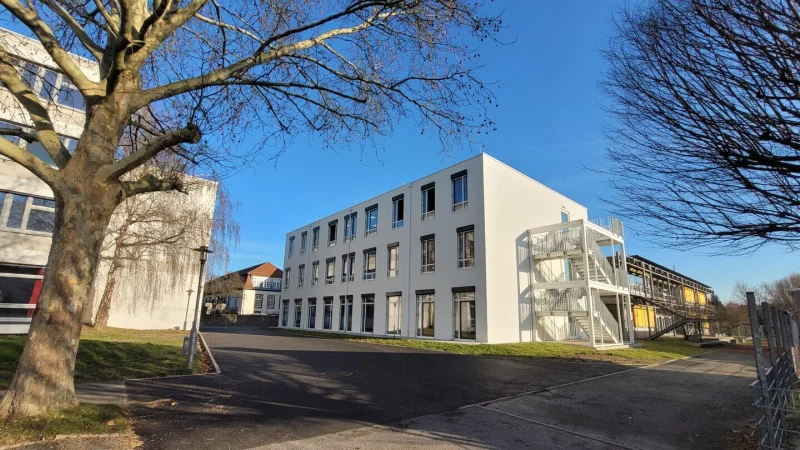 Seit 2024 ist der Klassentrakt (links) gesperrt, im vergangenen Jahr lie&szlig; die Stadt einen Modulbau (Mitte) errichten, um die gr&ouml;bste Raumnot zu lindern. - &copy; Katrin Kantelberg