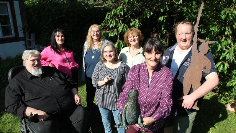 Immer bereit für eine gute Geschichte: die Kalletaler Wortakrobaten mit (von links) Lothar Schröer, Renate Langner-Mädel, Gabi Vößing, Elke Dießner, Katharina Birjukow, Ricarda Koch und Maurice Schröer im Garten der „Erzähldeele“ an der Weser in Erder. Dort sind auch ein Frosch und ein kleiner Hermann zu Hause. - © Jens Rademacher