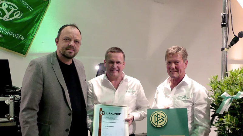 Timo Franz-Sauerbier vom Fu&szlig;ball- und Leichtathletik-Verband Lemgo &uuml;bergibt eine Urkunde und ein gro&szlig;es Ehrenschild an Rolf Thoren und Klaus Lhotzky (von links). - &copy; Rudi Rudolph