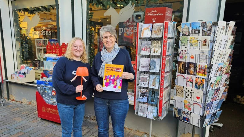 Inga Kunz (links, Inhaberin der Buchhandlung Pegasus) und Christiane Osterhage (Gleichstellungsbeauftragte der Alten Hansestadt Lemgo) setzen mit orangen Leuchten ein Zeichen gegen Gewalt gegen Frauen und M&auml;dchen. - &copy; Stadt Lemgo