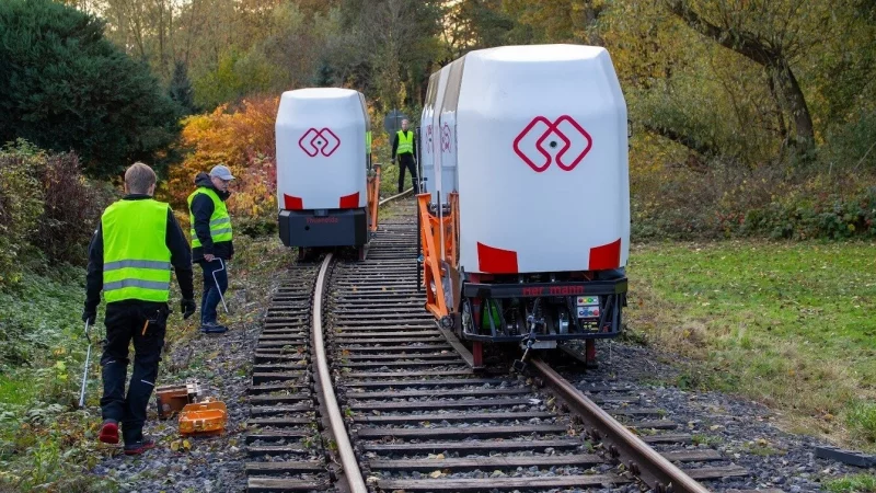 Die Monocabs sind auf der Teststrecke in Extertal ohne die orangefarbene Fangvorrichtung unterwegs und fahren aneinander vorbei. F&uuml;r alle F&auml;lle sind unter den Fahrzeugen Kufen angebracht, die aber in der Luft schweben, w&auml;hrend die Monocabs auf einer Schiene balancieren. - &copy; Peter Wehowsky