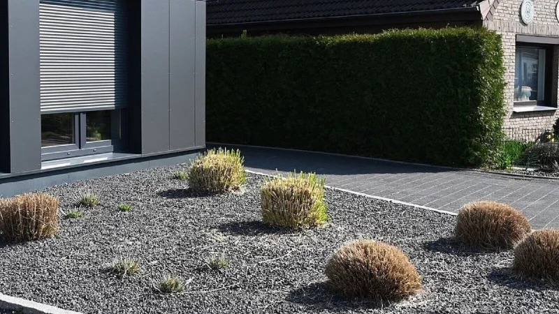 Komplett abgedeckt: Pflanzen ragen aus einem Vorgarten mit grauen und schwarzen Kieselsteinen. Der Boden ist weitgehend versiegelt. - © Carmen Jaspersen
