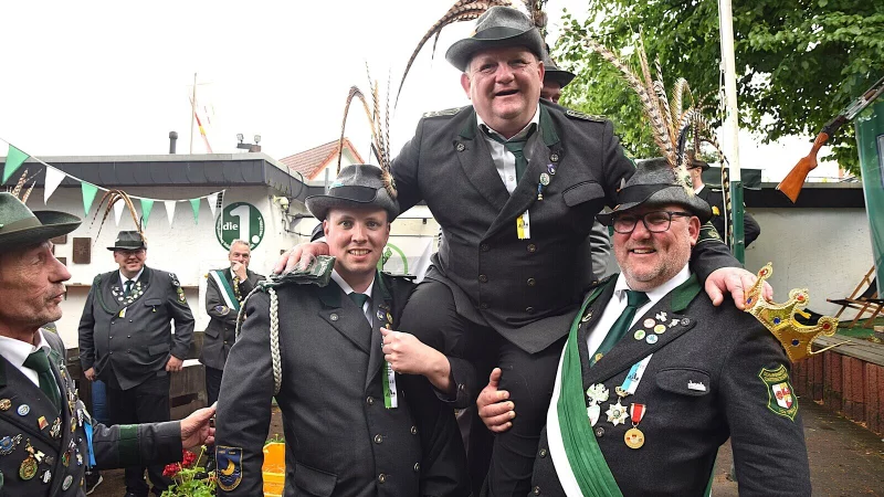 Nach dem entscheidenden Schuss wird Sören Grote als neuer Schützen-Kaiser von Simon Maske (l.) und seinem Bruder Robin Grote auf die Schultern genommen und durch die Reihen getragen. - © Karin Prignitz