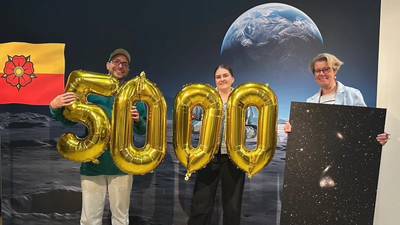 5000. Besucherin bei der Astronomie-Ausstellung im Weserrenaissance-Museum Schloss Brake: Museumsleiterin Silvia Herrmann (rechts) überreicht Celin Plener und Hayder Redzic aus Detmold eine von Klaus Eikmeier erstellte Fotografie aus dem Weltall. - © Alina Menkhoff