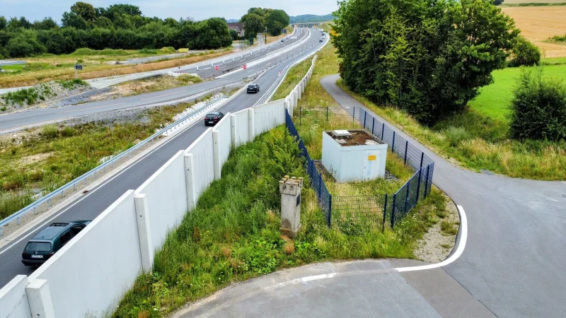 Der Grenzstein ist zwischen der Schallschutzmauer und einem Drahtzaun eingepfercht. F&uuml;r Autofahrer ist er unsichtbar, auch Radler m&uuml;ssen genau hinschauen.
Foto: Eike J. Horstmann - &copy; Eike J. Horstmann