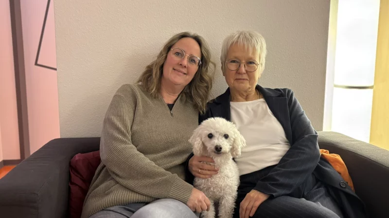 Verwaltungsangstellte Verena Mischke (links) und Dr. med. Sigrid H&auml;gele sitzen mit Therapieh&uuml;ndin "Eva" auf dem Sofa. - &copy; Jan Schillmann