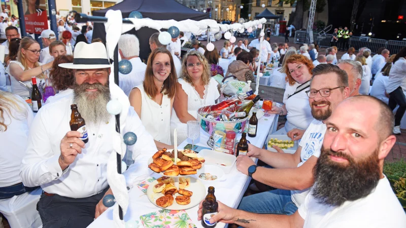 Weiß gekleidet, Snacks auf dem Tisch, ein Getränk in der Hand: Das "Dinner in White" auf dem Lagenser Marktplatz ist ein geselliges Event. - © Nicole Ellerbrake