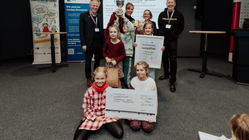 Stolz auf Urkunde und Scheck: Kinder der Grundschule Nord gemeinsam mit Ocke Hamann von der IHK (von links), Ministerin Mona Neubaur, Schulleiterin Madleen Klarhorst und Moderator Peter Abelmann. - &copy; Grundschule Nord