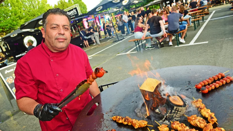Ali Dourmous aus Lippstadt bereitet Souflakispieße und griechische Bauernwurst am offenen Feuer zu. Den Gästen schmeckt es. - © Nicole Ellerbrake