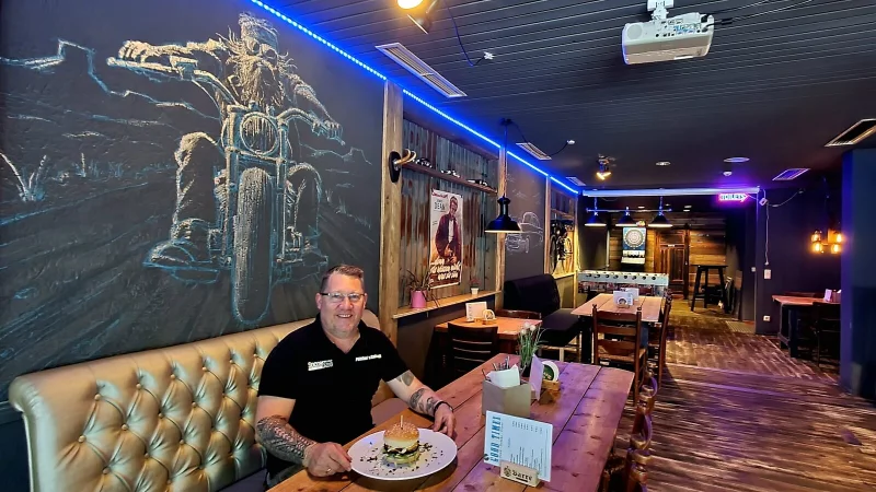 Peter P&ouml;hlker sitzt in seinem neuesten "Sch&auml;tzchen", dem "Good Times", vor einem Burger - um ihn herum l&auml;ssiger US-Biker-Style. - &copy; Kurt Ehmke