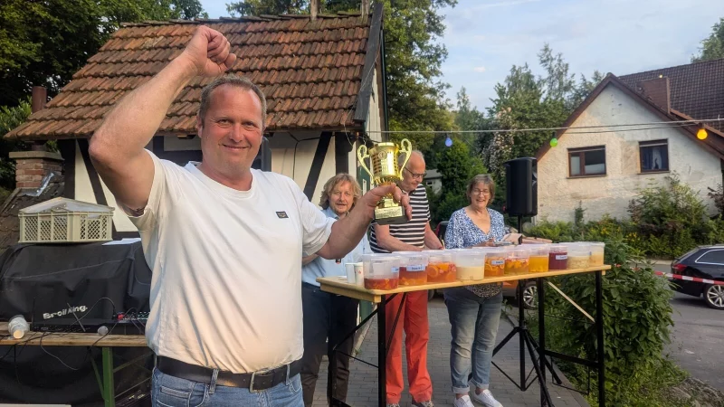 Er ist Bavenhausens neuer Bowle-König: Mario Schleef mit Wanderpokal. Im Hintergrund von links die Jury: Thorsten Rosenau, Dieter Hartwig und Iris Schön. - © Heimatverein Bavenhausen