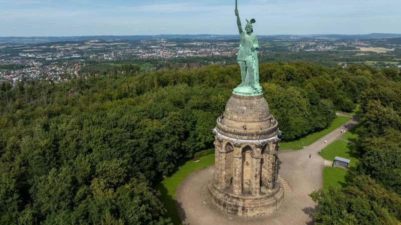 Blick auf das Hermannsdenkmal, Deutschlands gr&ouml;&szlig;te Statue, in den H&ouml;hen des Teutoburger Waldes. Mehr als eine halbe Millionen Menschen besuchen den Ort j&auml;hrlich. Am 16. August feiert der zust&auml;ndige Landesverband Lippe den 150. Geburtstag des Hermannsdenkmals (Architektonische H&ouml;he: 53 Meter) mit einem gro&szlig;en Familienfest. (Luftbild mit einer Drohne) (zu dpa: &laquo;Mythos und Geschichte: Das Hermannsdenkmal wird 150&raquo;) - &copy; Friso Gentsch/dpa