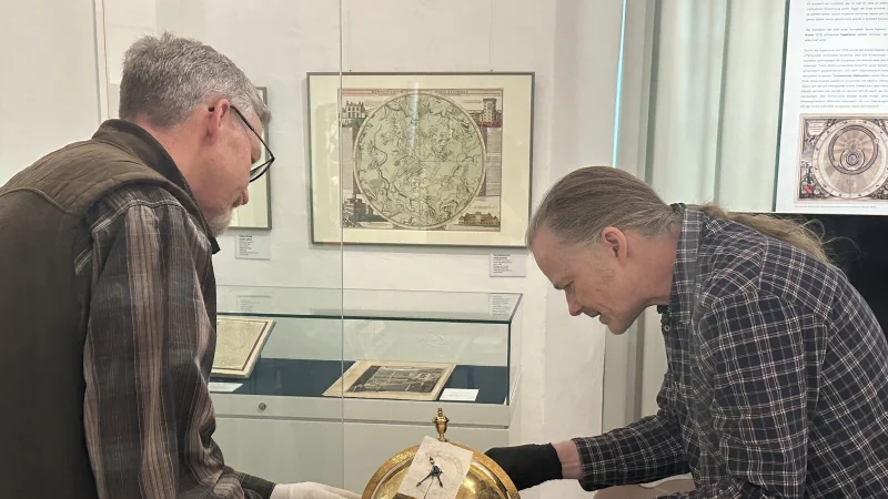 Mit schwarzen Handschuhen ausgerüstet holt der Restaurator Michael Beck (rechts) aus Kassel vorsichtig den Himmelsglobus aus der Vitrine und platziert ihn auf einem mit Seidenpapier ausgelegten Tisch. Thomas Senke (links), Techniker im Weserrenaissance-Museum Schloss Brake hilft beim Verpacken und beim Rücktransport der Leihgaben. - © Weserrenaissance-Museum