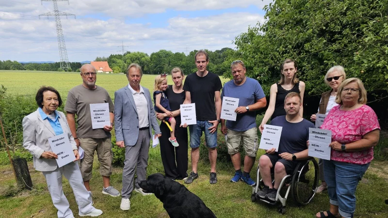 Ingrid Schmedding (von links), Ralf Mellies, Ferdinand Schmedding, Karina, Jan und Tabea Eke, Christian Dietz, Irina und Danilo Schmidt, Margarete Hilbrink und Martina Mellies stehen vor dem Feld, auf dem zwei große Windräder gebaut werden sollen. Sie protestieren dagegen und gründen eine Bürgerintiative. - © Astrid Sewing