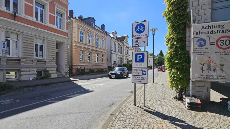 An der Freiligrathstraße in Detmold steht noch ein Transparent, was übersichtlich die Regeln in einer Fahrradstraße erklärt. Baulich ist an der Straße allerdings nicht viel verändert worden. Ein paar Parkplätze wurden in einen "Vorbeifahr-Streifen" für Radler umgewandelt und kurz vor der Ampel ist eine große Haltezone für Fahrradfahrer auf den Asphalt gesprüht worden. - © Jost Wolf