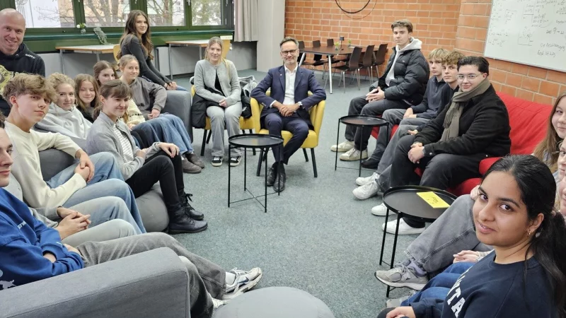 Schulleiter Dr. Claus Hilbing (Mitte) sitzt mit dem Erdkunde-Kurs der EF von Heiner Beckmann (links) in der "Senior Lounge", im Oberstufenraum des Grabbe-Gymnasiums. - © Jost Wolf