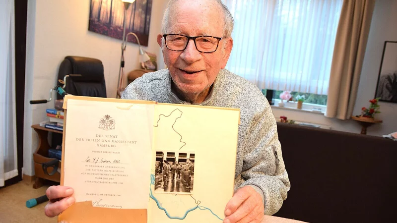 John Gibson, der im Januar 89 Jahre alt wird, h&auml;lt die Urkunde in H&auml;nden, die er im Jahr 1962 nach seinem Einsatz bei der Sturmflugkatastrophe in Hamburg bekommen hat. Daneben ist ein Bild aus seiner Zeit als Soldat zu sehen. - &copy; Karin Prignitz