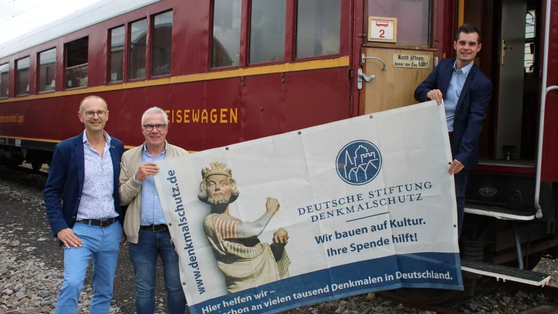 Frank Budde (Stiftung Denkmalschutz, von links) und Holger Brokemper ("WestLotto") stehen mit Betriebsleiter Raphael Kahlert vor dem historischen Speisewagen aus dem Jahr 1936. - © Lorraine Brinkmann