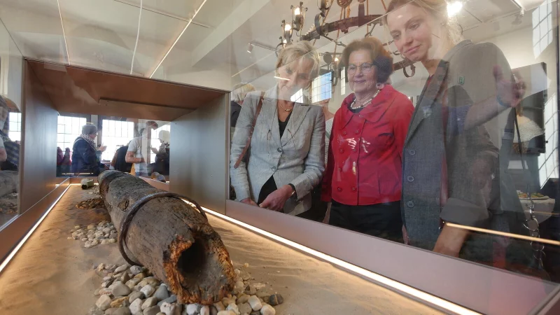 Dr. Ute Röder (NRW-Stiftung, von links), Anne Oelers-Albertin (Heimatverein Horn) und Dr. Stella Junger-Schwenner (stellvertretende Bürgermeisterin) schauen sich die neue Präsentation des Holz-Wasserrohrs im Roten Saal des Burgmuseums an. - © Jost Wolf