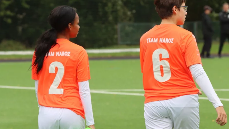 Hanna Ndjibila (links) und Carolin Silva Wagenbach vom TuS Eichholz-Remmighausen betreten mit orangenen Trikots mit der Aufschrift Team Naroz den Platz. Normalerweise spielt der TuS in Gr&uuml;n. - &copy; Sebastian Lucas