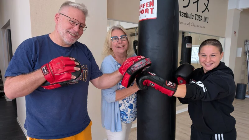 Kai Gutmann, Leiter der Sportschule Tosa Inu in Lemgo, demonstriert mit Boxweltmeisterin Beke Bas (rechts) die Arbeit mit sogenannten "Pratzen". Margret Hey (Mitte) leitet schon lange Selbsthilfegruppen zum Thema Parkinson und hat das neue Angebot ins Leben gerufen. - &copy; Annika Langhagel