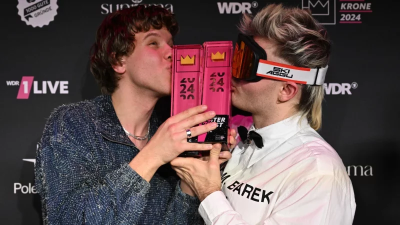 S&auml;nger Zartmann (l.) und Ski Aggu k&uuml;ssen nach der Verleihung des Musikpreises im Lokschuppen Bielefeld ihre Preise. - &copy; David Inderlied/dpa