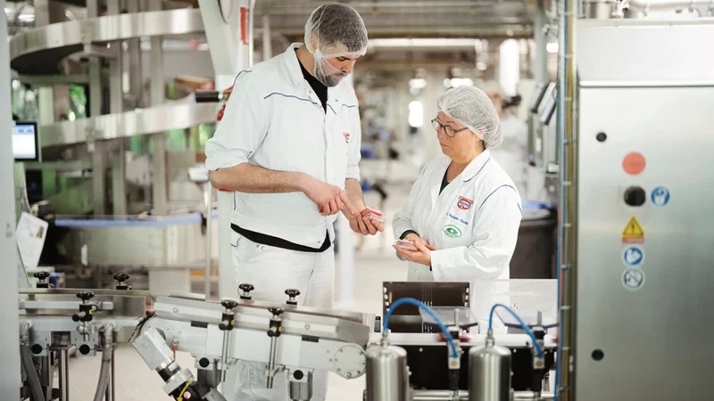 Heidrun Martmann-Geydan und Steven Richter in der Nahrungsmittelproduktion im Oetkerwerk Brackwede im Jubil&auml;umsjahr 2025. - &copy; Dr. August Oetker KG