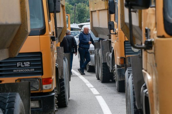 Zwei serbische Männer stehen neben einer Straße, die zum Grenzübergang Jarinje im Norden des Kosovo führt. - © Visar Kryeziu/AP/dpa