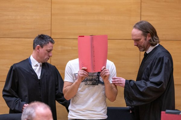 Beim Beginn im Prozess um den Vorwurf einer Vergewaltigung vor einem Club in Herford steht einer der beiden Hauptangeklagten (M) neben seinen Anwälten. - © Guido Kirchner/dpa