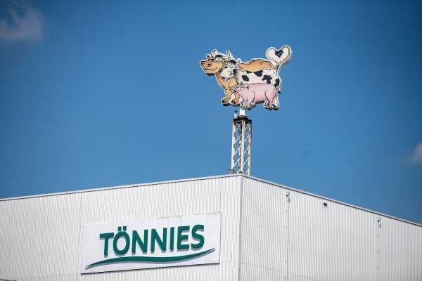 Auf dem Dach eines Gebäudes auf dem Werksgelände steht das Logo der Firma Tönnies in Form von zwei Kühen und einem Schwein. - © Guido Kirchner/dpa
