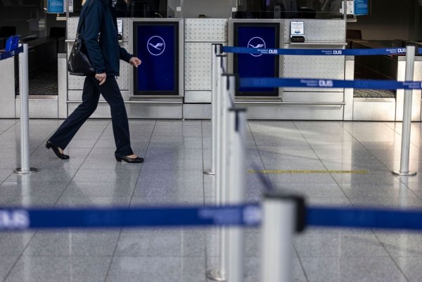 Eine Frau läuft an Lufthansa-Schaltern zum Check-In am Flughafen Düsseldorf vorbei. - © Christoph Reichwein/dpa/Archivbild