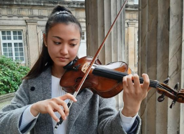 In ihrem Element: Gina Keiko Friesicke steht mit ihrer Geige vor der Musikhochschule in Detmold und entlockt ihrem Instument einige Töne. - © Julia Kube
