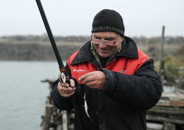 Ein Angler hat einen kleinen Fisch gefangen. - © picture alliance/dpa