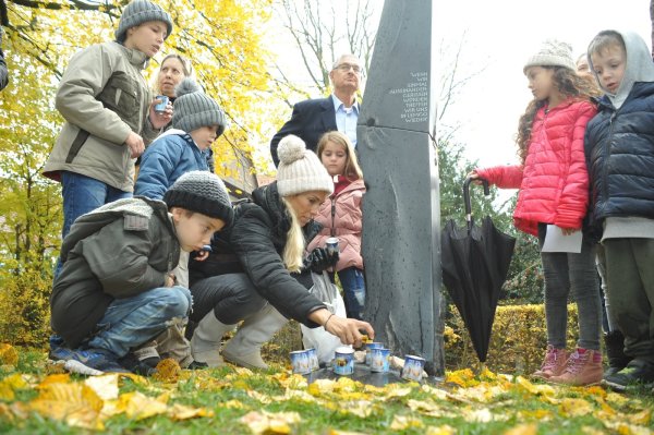 Nachfahren von Karla Raveh, darunter auch Enkel und bereits Urenkel, legen am Denkmal für Lemgos Ehrenbürgerin am Wall Steine nieder und zünden Kerzen an. - © Nicole Ellerbrake