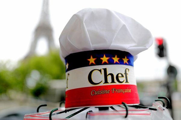 Eine Kochmütze wird an einem Souvenirstand beim Eiffelturm angeboten. In Frankreichs Gastronomie werden viele Stellen von Ausländern besetzt. - © Michael Kappeler/dpa