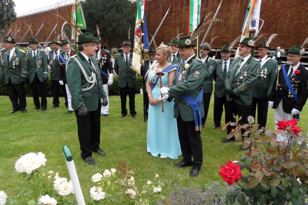 Königliche Pracht: Aufmarschoffizier Jürgen Schröder (links) überreicht den aktuellen Majestäten Sascha Ruge und Britta Ruge-Koring ein Schild, das künftig „ihre" Rose zieren wird. Mittlerweile ist es der fünfte Strauch, der seit 2009 von Salzufler Regenten als Erinnerung im  Rosengarten am Gradierwerk gepflanzt worden ist. - © Foto: Privat