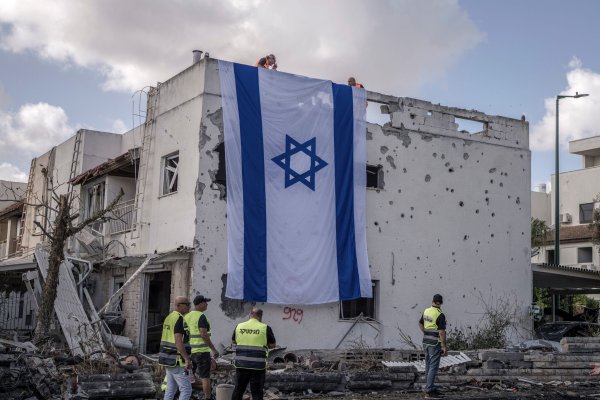 Eine riesige israelische Fahne hängt vom Dach eines beschädigten Gebäudes in Kiriat Bialik. - © Ilia Yefimovich/dpa