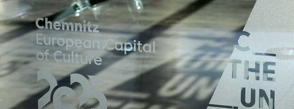 Das Motto der Kulturhauptstadt Chemnitz «C The Unseen» zeichnet sich als Schatten auf dem Boden des Welcome Centers in Chemnitz ab. (Archivbild) - © Hendrik Schmidt/dpa