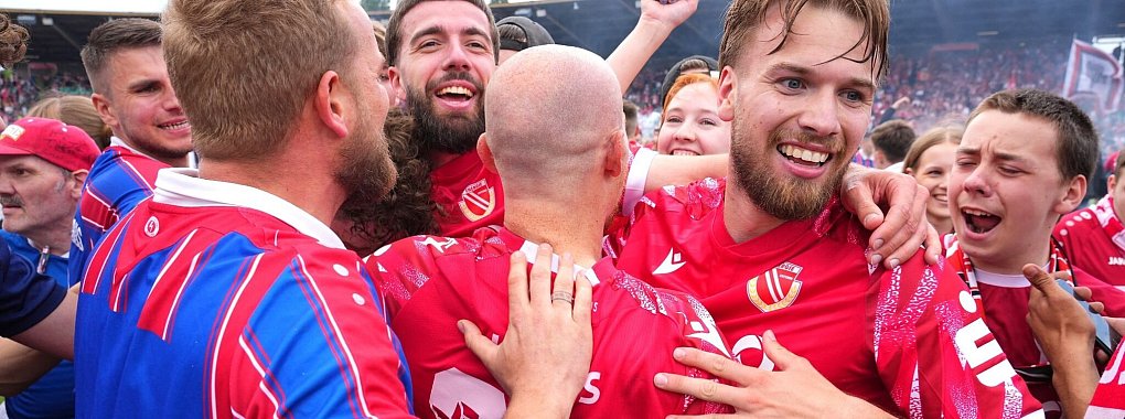 Die Spieler von Energie Cottbus bejubeln nach Schlusspfiff und Platzsturm den Aufstieg mit den Fans. - © Soeren Stache/dpa