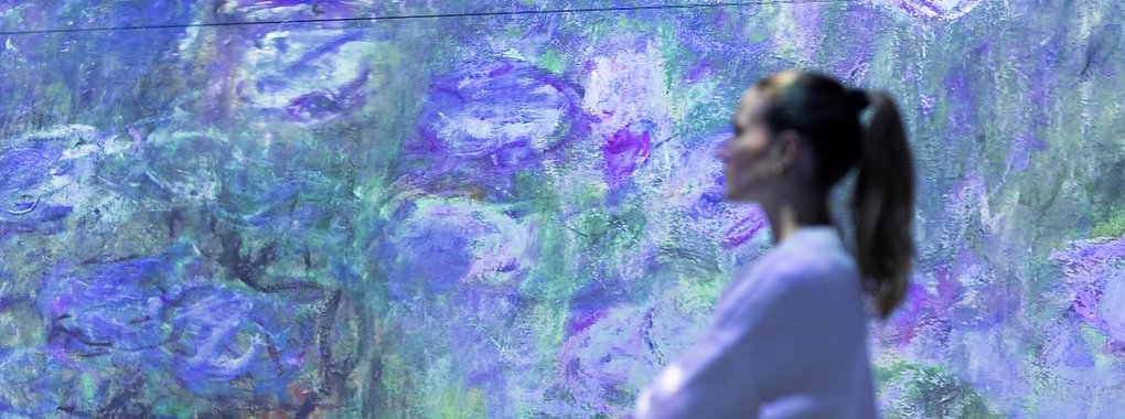 Eine Mitarbeiterin steht in der multimedialen Ausstellung «Monets Garten». - © Michael Matthey/dpa