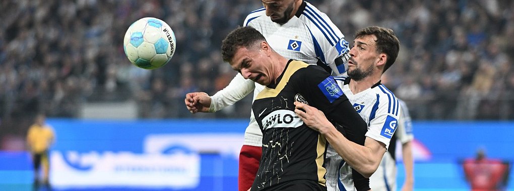 Elversbergs Fisnik Asllani (vorn, l) wird von den beiden HSV-Spieler Ludovit Reis und Jonas Meffert geblockt. - © Michael Schwartz/dpa