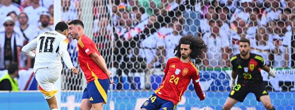 Spaniens Marc Cucurella (M) bekommt den Schuss von Deutschlands Jamal Musiala an den Arm. - &copy; Tom Weller/dpa